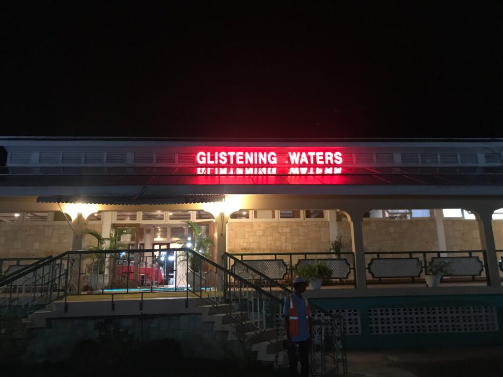 Glistening Waters restaurant and marina entrance at night in Falmouth Jamaica with red neon sign