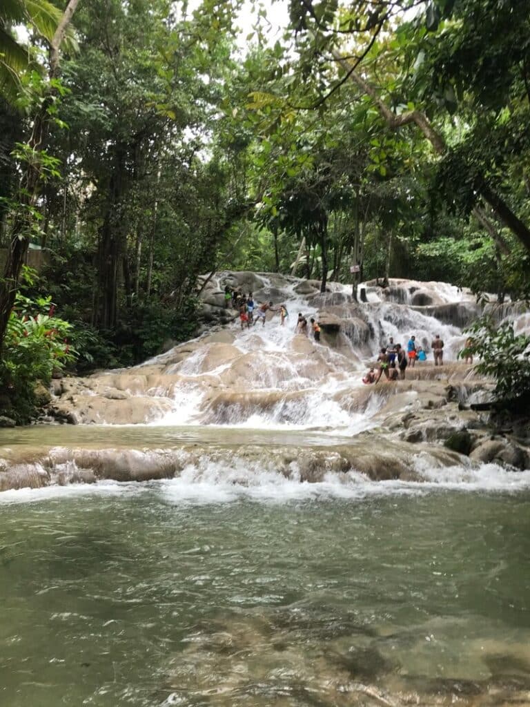 Large group of visitors climbing Dunn’s River Falls waterfall in Jamaica.