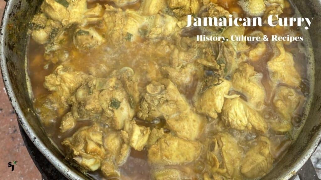 Jamaican curry chicken cooking in a Dutch pot on an outdoor coal stove