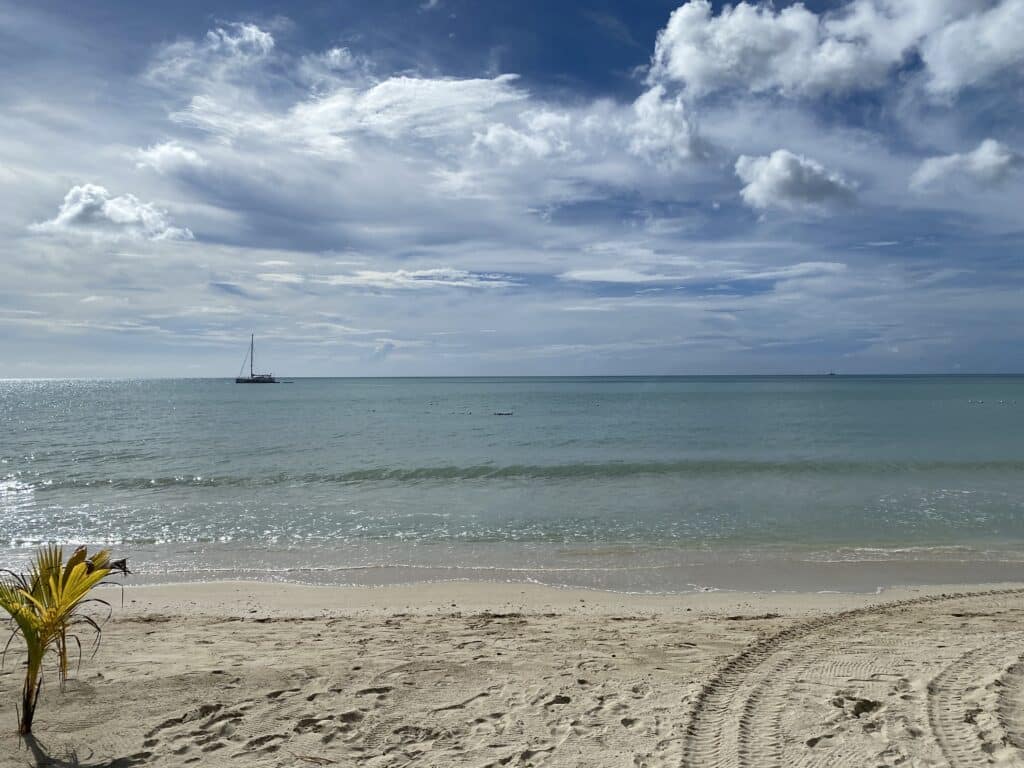 Quiet stretch of Seven Mile Beach Jamaica with calm water and distant boat