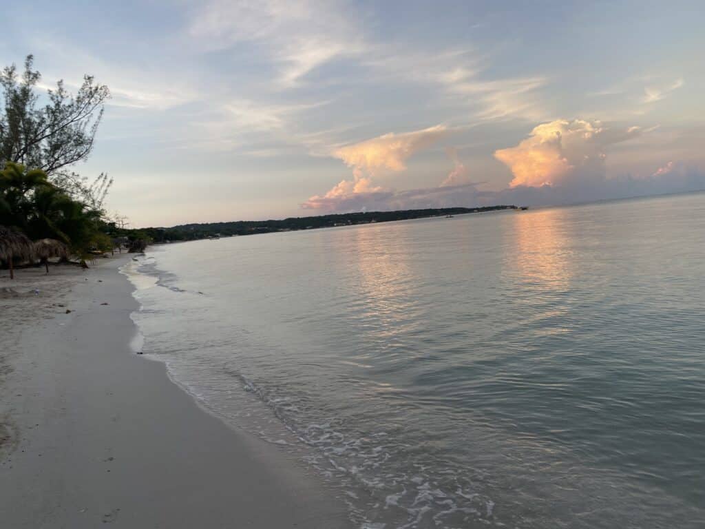 Wide shoreline view of Seven Mile Beach, Jamaica at sunset