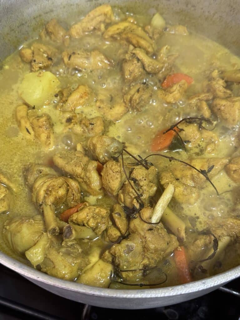 Chopped Jamaican curry chicken with potatoes and carrots in a pot