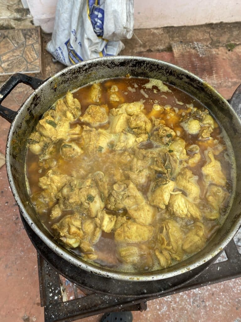 Jamaican curry chicken simmering in a Jamaican Dutch pot on an outdoor stove