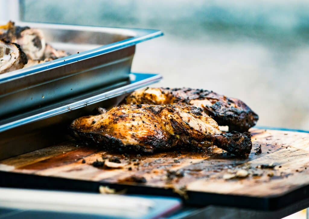 Jamaican jerk chicken freshly cooked showing char and seasoning crust on wooden board