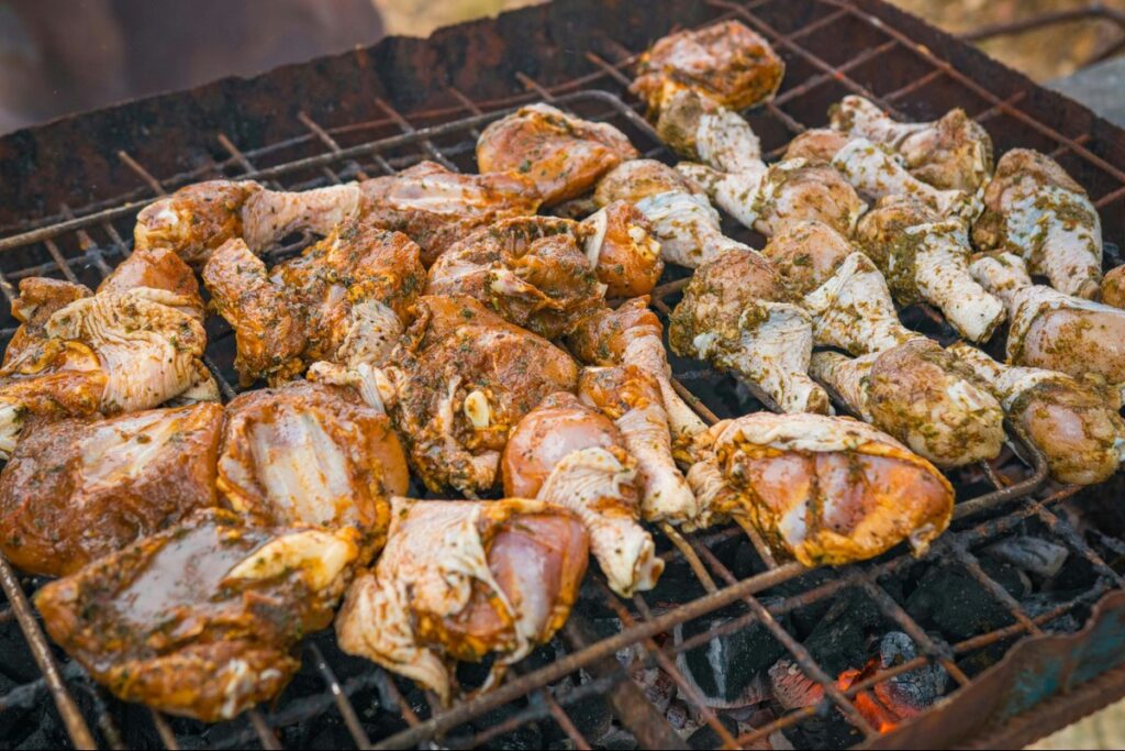Jamaican jerk chicken marinated in seasoning cooking over charcoal grill