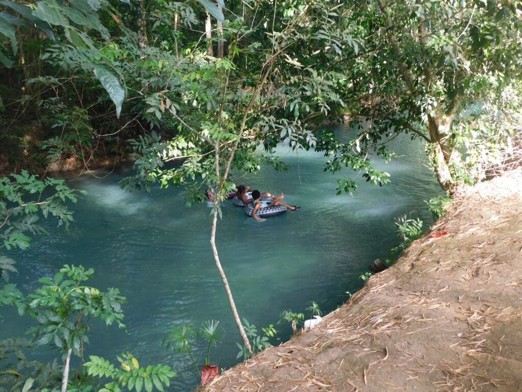 Two people river tubing on White River Jamaica, floating through lush tropical jungle