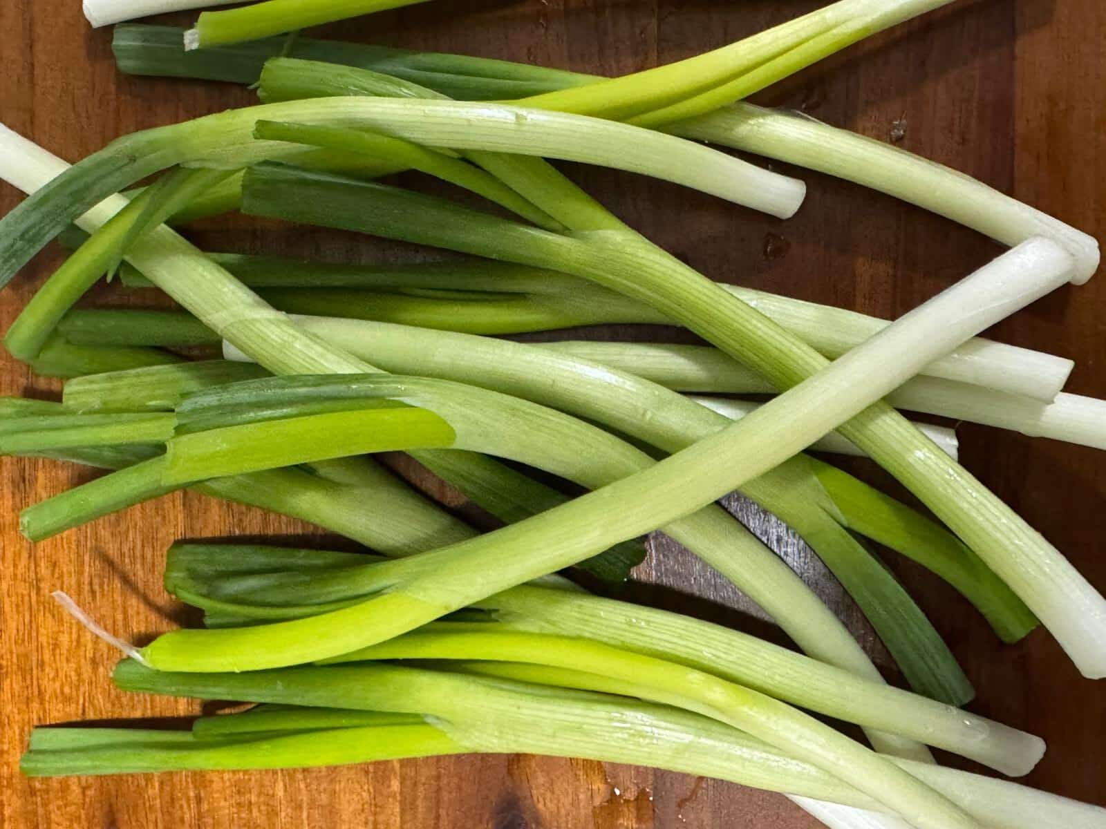 Fresh scallion (green onion) sliced on a wooden cutting board for Jamaican seasoning