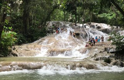 Large group of visitors climbing Dunn’s River Falls waterfall in Jamaica.